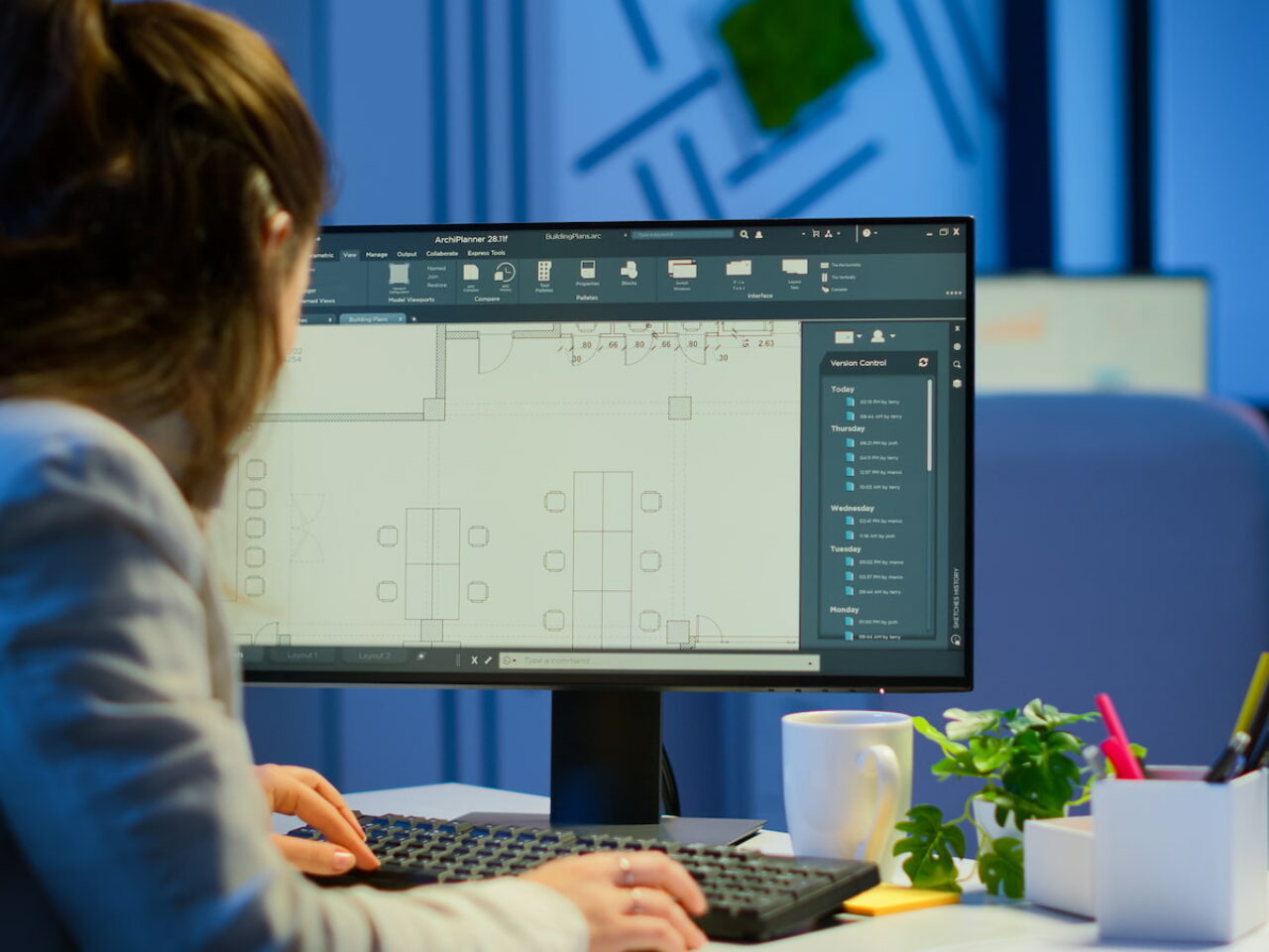 Over the shoulder shot of engineer working with architectural plans, cad software on desktop computer. Designer using arhitecture blueprints of buildings working overtime, creating and studying